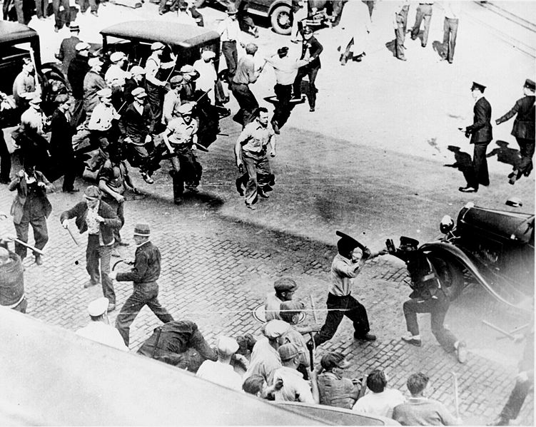 Black and White photo from 1934, teamsters and police can be seen with batons raised, ready to strike.